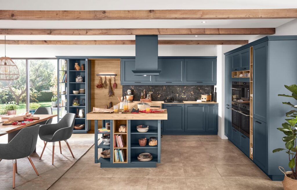 Fjord-blue framed cabinets with a patterned backsplash and adjacent dining area, showcasing the social aspect of country kitchens.