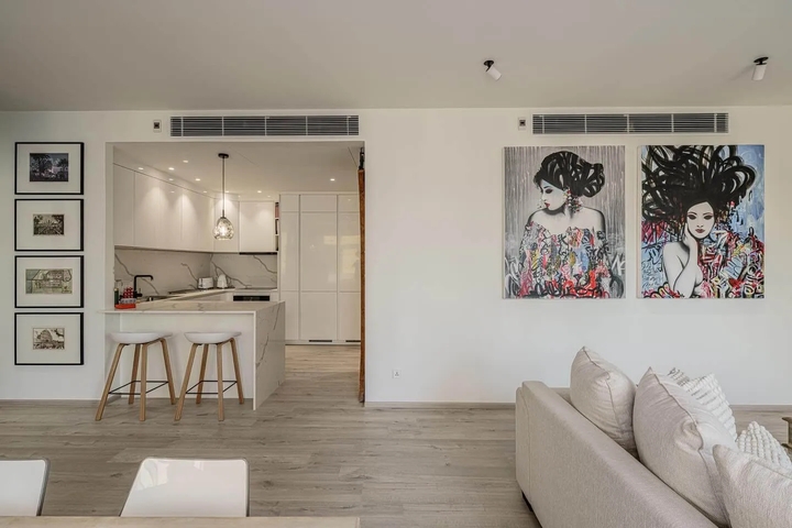 A spacious Bangkok condo featuring a high-gloss white kitchen bar that reflects natural light, enhancing the open feel of the living area in modern minimal kitchens.