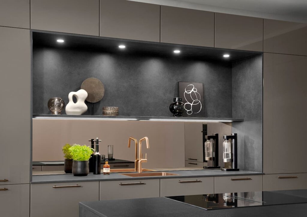 Close-up of a sleek minimalist kitchen niche featuring dark stone textures, handleless cabinetry, and integrated LED lighting that transforms the workspace into an atmospheric backdrop.