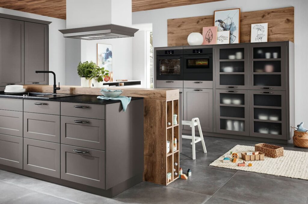 Grey framed kitchen cabinets with open wood shelving and glass displays in a natural living cottage style design.
