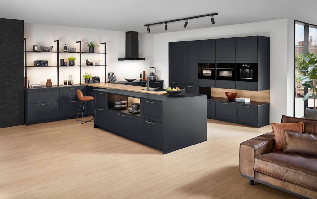 Spacious industrial loft kitchen with black cabinets and wood dining table exemplifying natural living design.